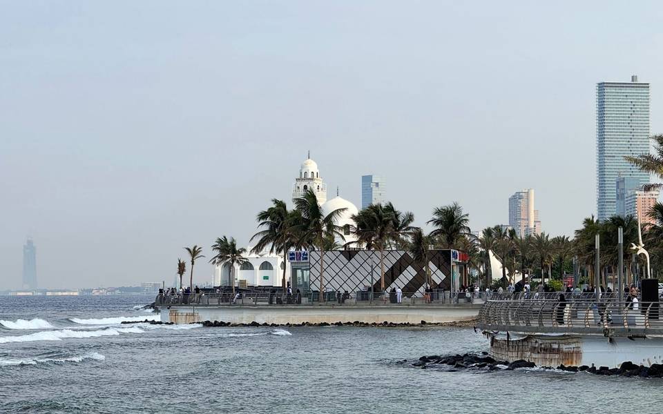 كورنيش جدة على البحر الأحمر بمسجد أبيض ونخيل ومبانٍ في الأفق